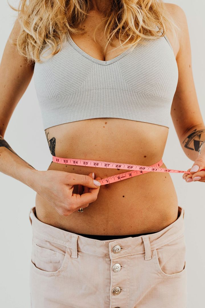 Woman measuring waist with pink tape